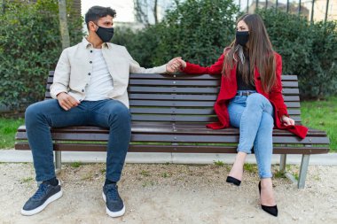 Kenarda oturan çift covid ya da coronavirüs konsepti için sosyal uzaklık