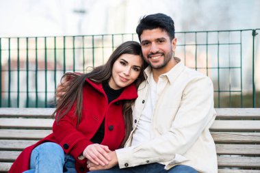 Mutlu çift bankta oturmuş gülümsüyor.