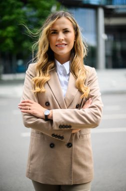 Kendine güvenen genç bayan yönetici modern bir şehir ortamında kollarını kavuşturdu.