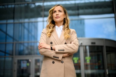 Kendine güvenen genç bayan yönetici modern bir şehir ortamında kollarını kavuşturdu.