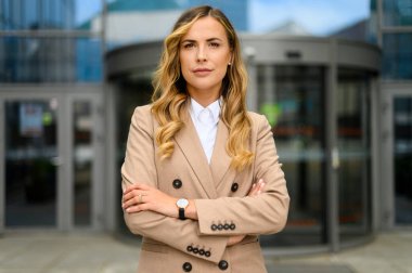 Kendine güvenen genç bayan yönetici modern bir şehir ortamında kollarını kavuşturdu.