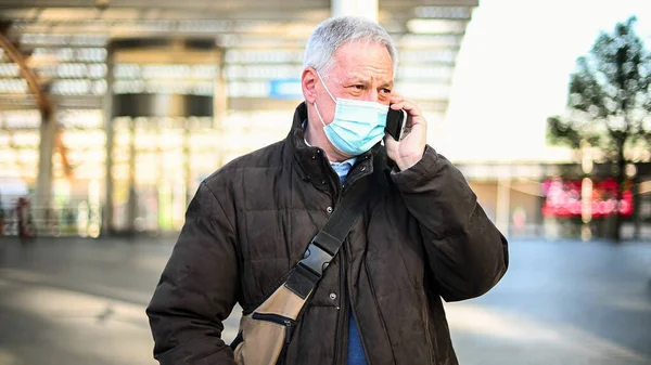 携帯電話のシニア男屋外マスクを着て コロナウイルスの概念 — ストック写真
