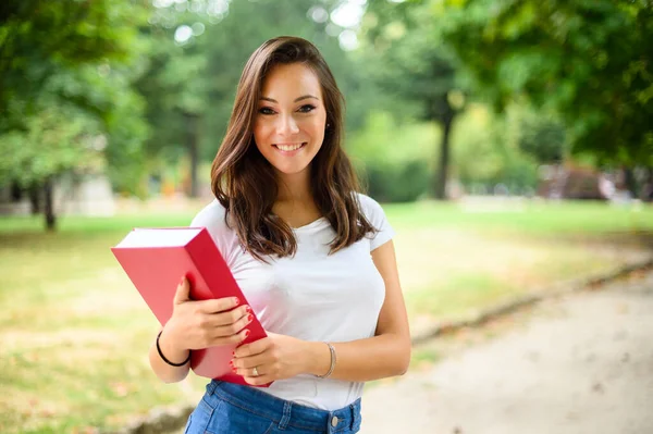 Beautiful female student holding a book outdoor