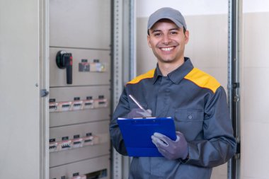 Dost elektrikçi bir paneli incelerken bir belge yazıyor