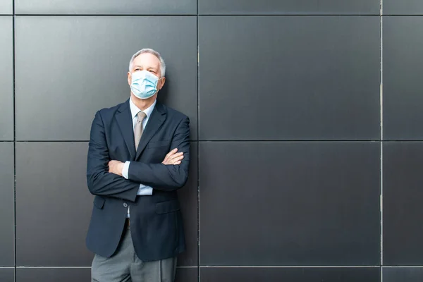 コロナウイルス コヴィドの概念黒壁の隣に立つ覆面のある高級ビジネスマン — ストック写真