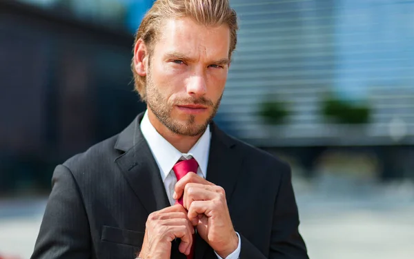 現代的な都市設定でハンサムなブロンド北欧ビジネスマン彼のネクタイを調整 — ストック写真
