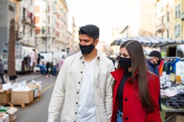 Sokak pazarından alışveriş yapan maskeli genç bir çift. Covid Coronavirus konsepti.