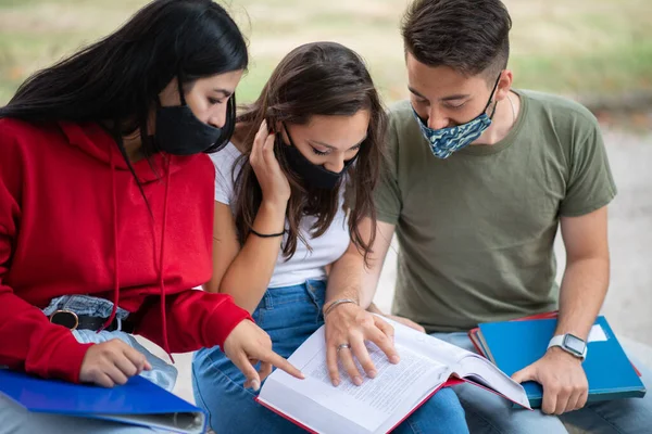 Tre Studenti Che Studiano Insieme Seduti Una Panchina All Aperto — Foto Stock