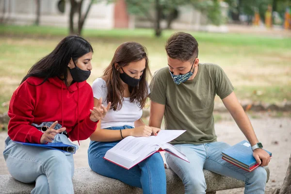 Tres Estudiantes Estudiando Juntos Sentados Banco Aire Libre Usando Máscaras —  Fotos de Stock