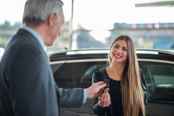 Young woman taking the keys for her car in a showroom