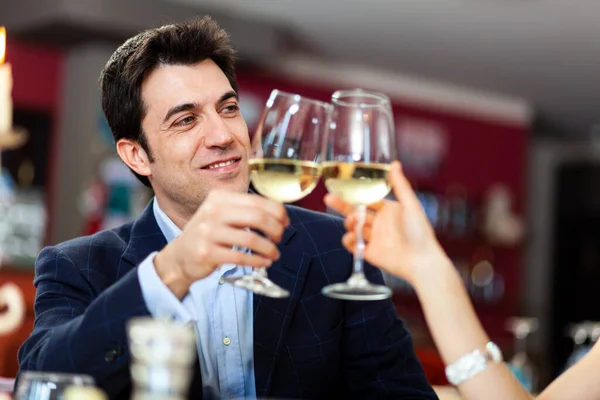 Couple toasting wine glasses in a restaurant