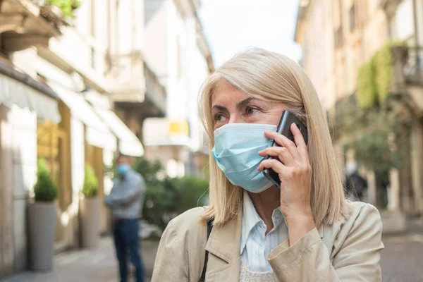 マスクをしながら電話をかける女性コロナウイルスはパンデミックを引き起こしました — ストック写真