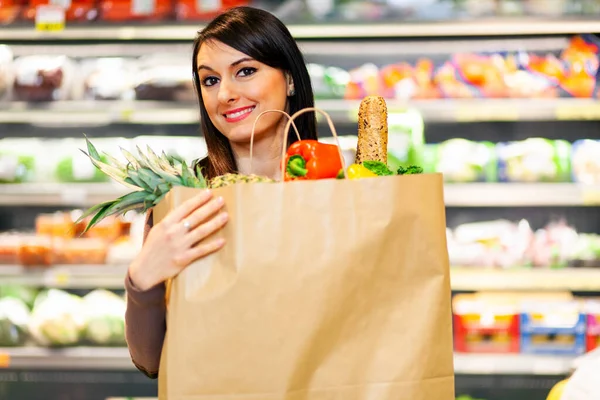 野菜たっぷりの袋を持った笑顔の女性 — ストック写真