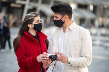 Covid veya Coronavirus salgını sırasında şehirde fotoğraf çeken iki genç turist.