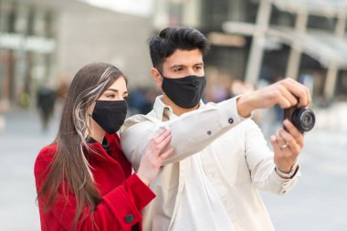 Covid veya Coronavirus salgını sırasında şehirde fotoğraf çeken iki genç turist.