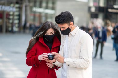 Covid veya Coronavirus salgını sırasında şehirde fotoğraf çeken iki genç turist.
