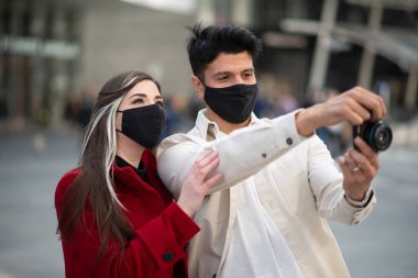 Covid veya Coronavirus salgını sırasında şehirde fotoğraf çeken iki genç turist.