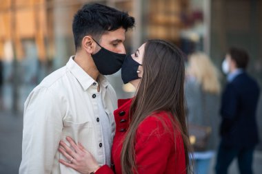 Covid ya da Coronavirus maskesi takarken öpüşen çift, salgın aşk konsepti