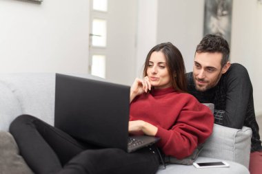 Evlerinde dizüstü bilgisayar kullanan mutlu bir çiftin portresi.