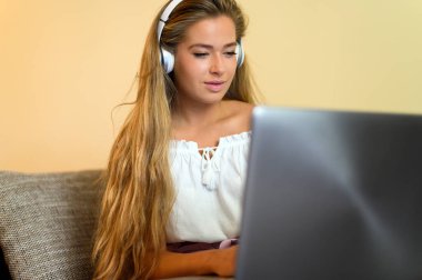 Kanepede dinlenirken dizüstü bilgisayar kullanan bir kadın.