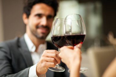 Yakışıklı adam bir bardak kırmızı şarap tadıyor.