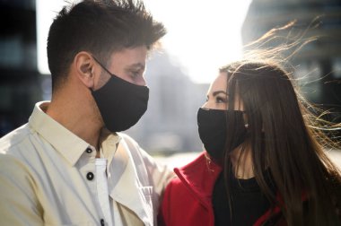 Romantik mutlu çift, Coronavirus Codemic 19 salgınına karşı maske takarak birbirlerinin gözlerinin içine bakıyor.