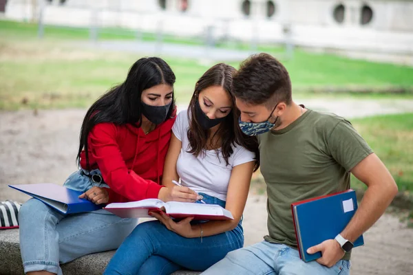 Trzech Studentów Studiujących Razem Ławce Świeżym Powietrzu Noszących Maski Czasach — Zdjęcie stockowe