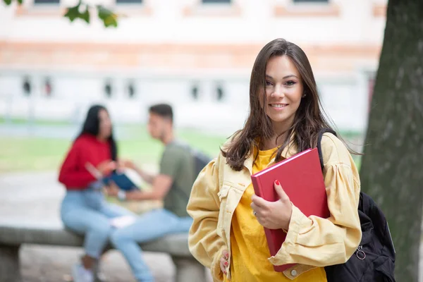 女学生在公园的一群朋友面前看书 — 图库照片