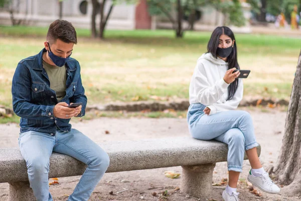 在公园里 年轻人在户外使用手机时 由于头皮病毒而与外界保持距离 — 图库照片