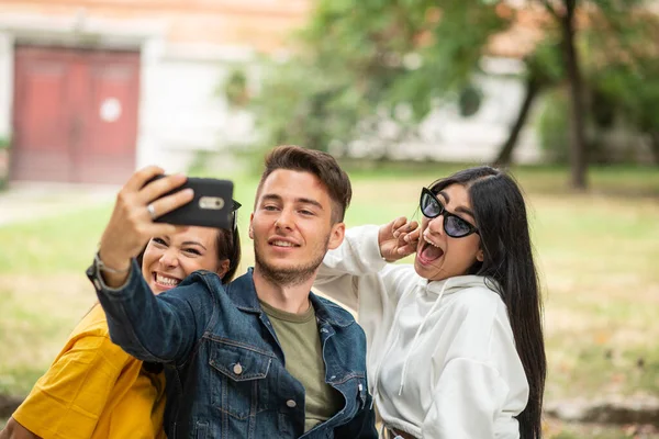 Wesoły Uśmiech Przyjaciół Parku Siedzi Ławce Robi Selfie Pomocą Smartfona — Zdjęcie stockowe