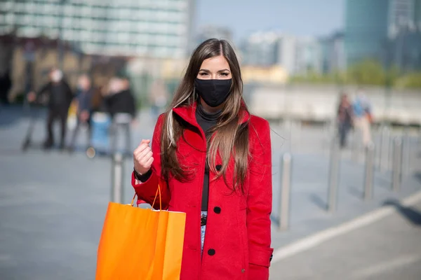 マスク Covidとコロナウイルスの概念を身に着けている間ショッピングバッグを持っている仮面の若い女性 — ストック写真