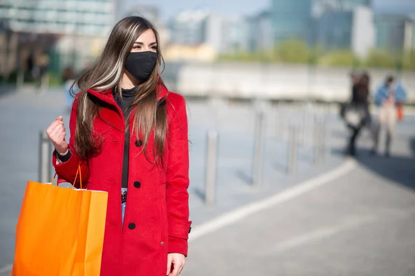 マスク Covidとコロナウイルスの概念を身に着けている間ショッピングバッグを持っている仮面の若い女性 — ストック写真