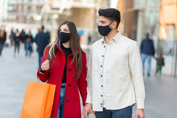 コヴィドとコロナウイルスのショッピング ショッピングバッグを持っている間に街を歩く若いカップル — ストック写真