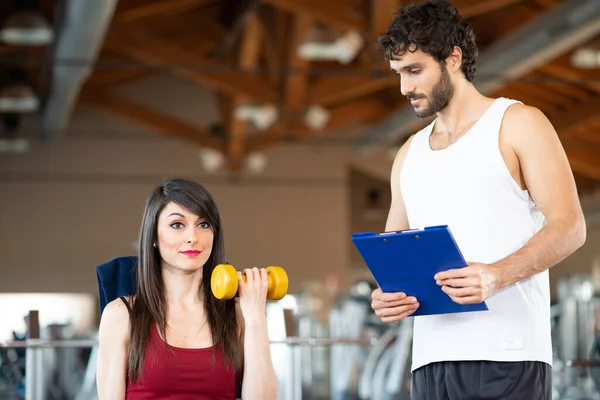 Vrouw Traint Een Sportschool Terwijl Haar Personal Trainer Kijkt Naar — Stockfoto