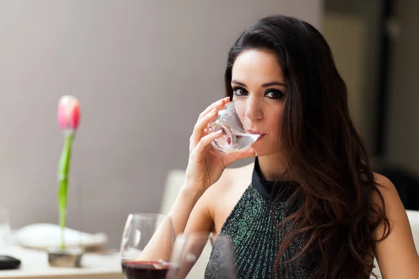 Beautiful young lady drinking water in restaurant