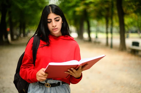 漂亮的女学生在户外拿着一本书 — 图库照片