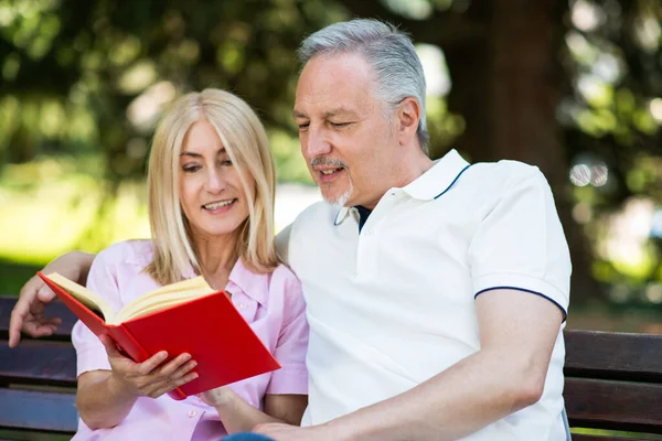 Coppia Matura Che Legge Libro Rosso Nel Parco — Foto Stock