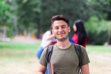 Üniversite kampüsünde yürüyen gülümseyen öğrenci.
