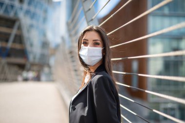 Köprünün yanında genç maskeli bir kadının portresi, covid ve coronavirus salgını konsepti