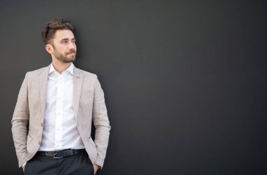 Siyah bir duvarın yanında duran yakışıklı bir iş adamı.