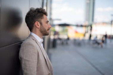 Şehir meydanında duvara yaslanan bir iş adamı