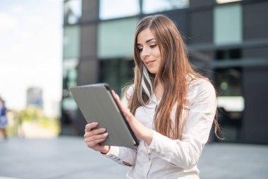 Ofisinin yanında tablet kullanan gülümseyen bir iş kadını.