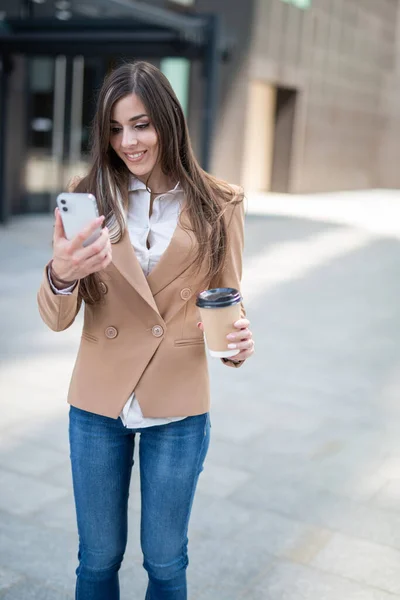 Mladá Podnikatelka Pomocí Svého Chytrého Telefonu Při Pití Kávy — Stock fotografie