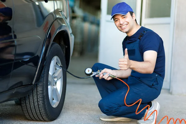 Lächelnder Mechaniker, der Reifen aufpumpt — Stockfoto