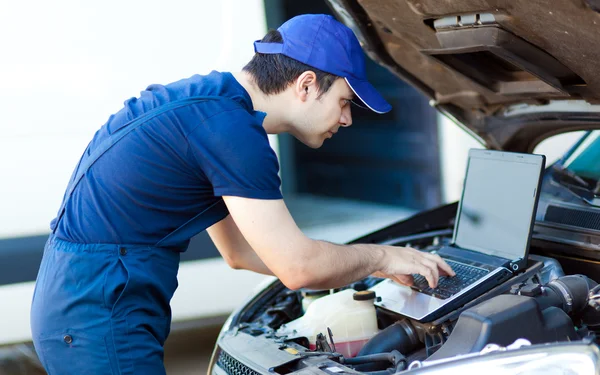 Mechanik za pomocą laptopa aby sprawdzić silnik samochodu — Zdjęcie stockowe