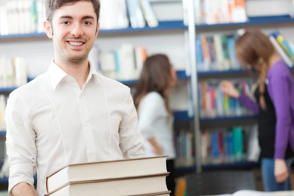 Tipo sosteniendo libros en la biblioteca — Foto de Stock