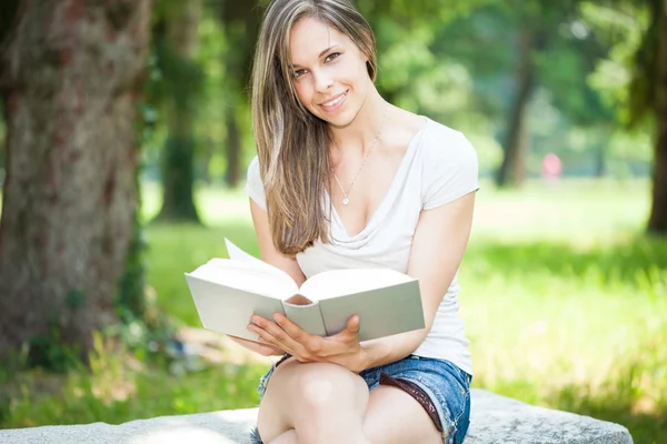 Park yerinde kitap okuyan bir kadın. — Stok fotoğraf