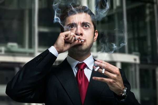 Empresário fumando muitos cigarros — Fotografia de Stock