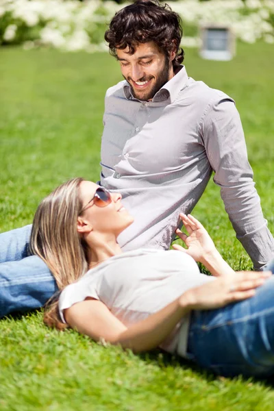 Jovem casal relaxante na grama — Fotografia de Stock