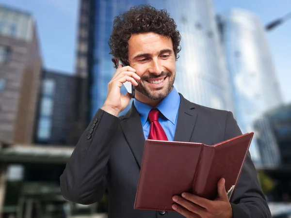 Reifer Geschäftsmann macht sich am Telefon Notizen — Stockfoto